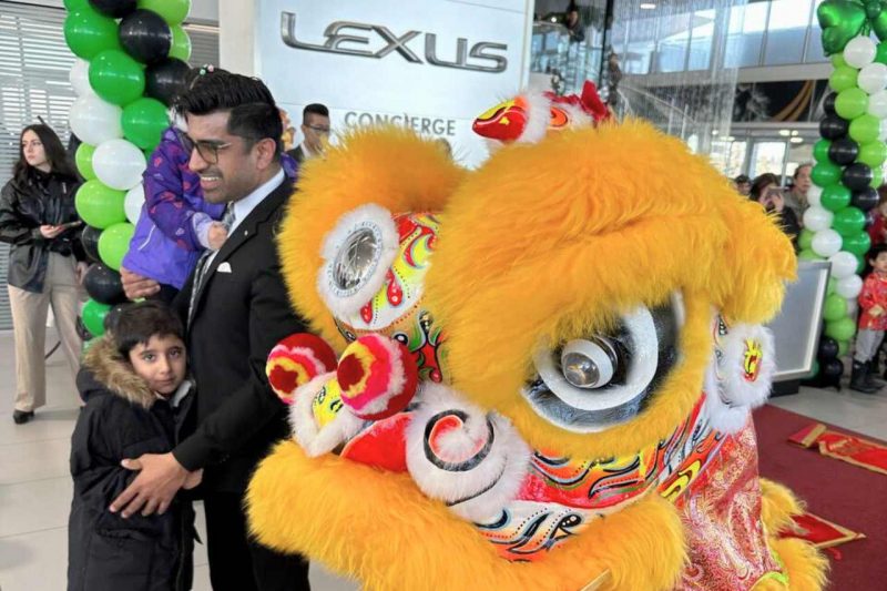 A chinese lion dancer poses with a young family.