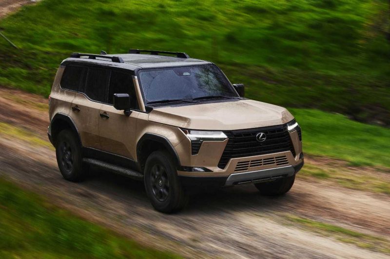 The Lexus GX SUV drives down a dirt road in a forest.