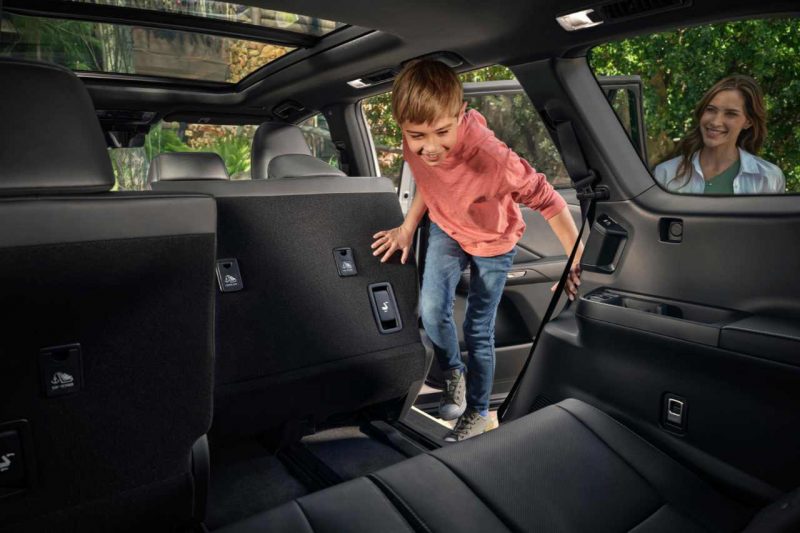 A child enters a SUV and climbs into the back seat.