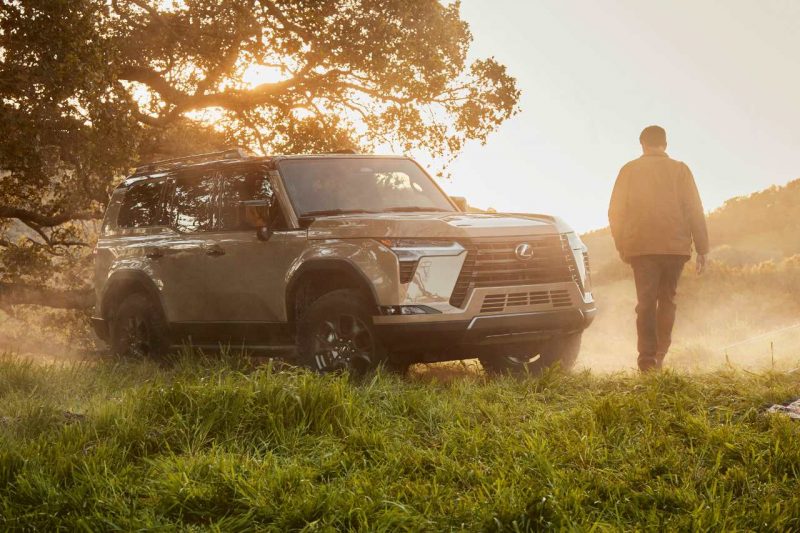 A man walks toward a GX SUV on a hill.