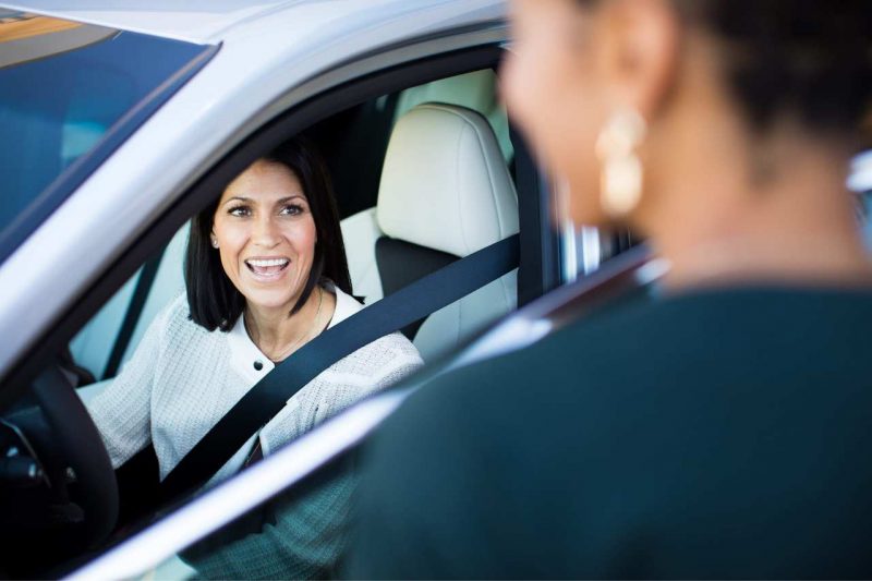 A woman smiles out the passenger door at a Lexus salesperson.