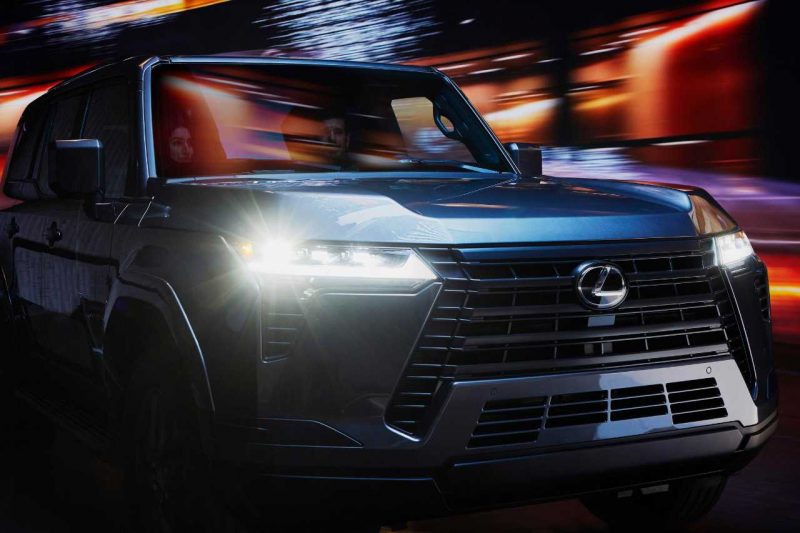 The 2024 Lexus TX SUV driving down a road at night.