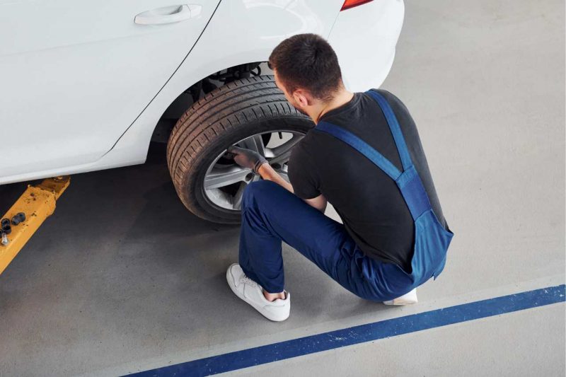 An auto mechanic removes and rotates the tires on a vehicle.
