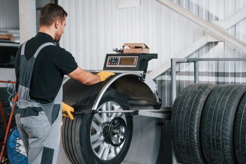 A mechanic tests the balance and alignment of a tire.