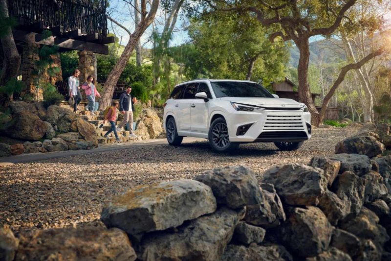The 2024 Lexus TX in white stands outside a family home.