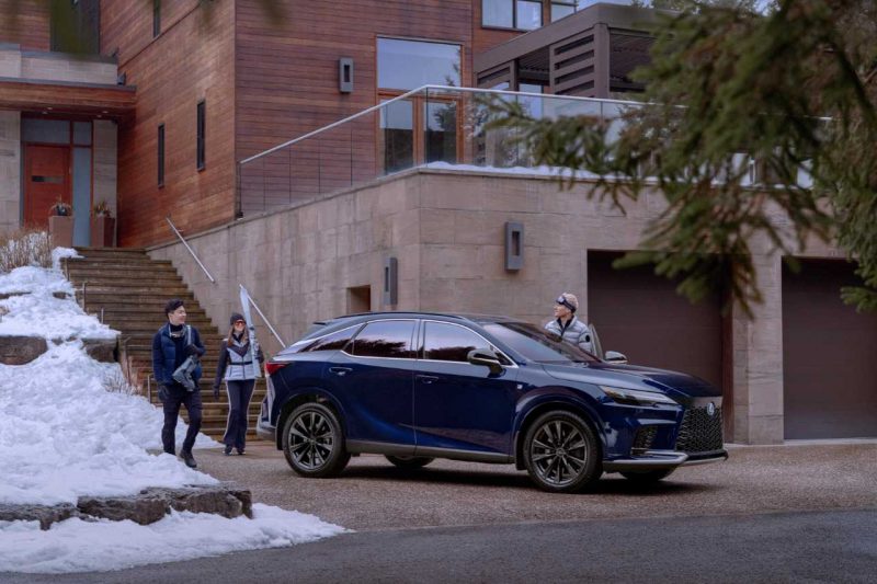 The 2024 Lexus RX SUV stands outside a modern home in the snow.